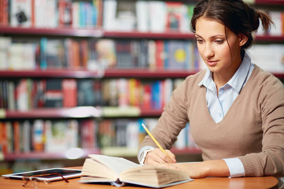 Estudiante en una biblioteca elaborando un trabajo