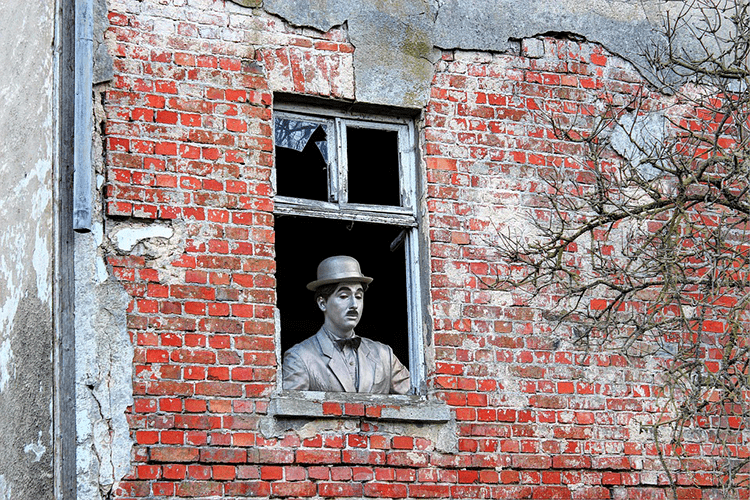 Fotografía de escultura de Chaplin que se asoma por una ventana