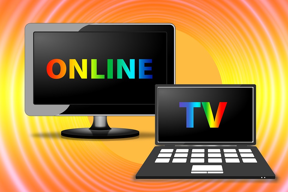 Monitores de una computadora de escritorio y una laptop, en cuyas pantallas aparecen las letras: “ONLINE” y  “TV”